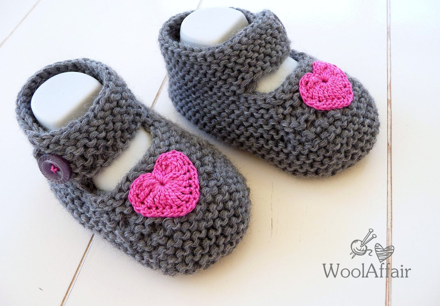 Strickanleitung für Babyballerinas: graue Strickschuhe mit pinkem Herz und Knopf