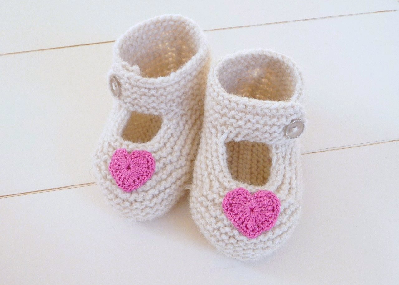 Strickanleitung für Babyballerinas: weiße Wollschuhe mit pinken Herzapplikationen